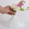 Une personne met un petit bouquet de rose dans un vase soliflore moderne en porcelaine de limoges blanche et brillante de chez l'atelier du blanc