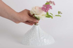 Une personne met un petit bouquet de rose dans un vase soliflore moderne en porcelaine de limoges blanche et brillante de chez l'atelier du blanc