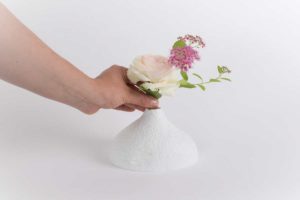 Une personne met un bouquet de fleur rose dans un vase soliflore en porcelaine de limoges blanche en biscuit mat de chez l'atelier du blanc